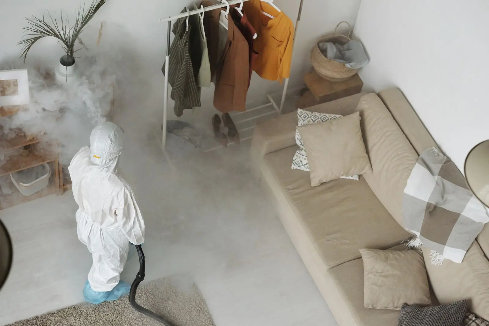 Professional in protective equipment treating a home interior